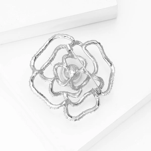 Dettaglio spilla a rosa argentata con petali traforati a strati e finitura in lega lucida fine