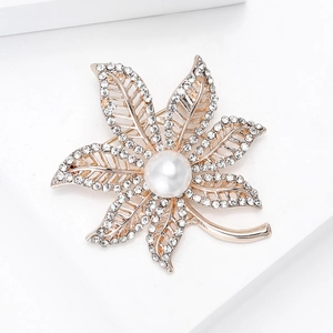 Macro detail of luxury maple leaf brooch with sparkling crystals and a white pearl center