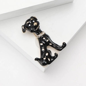 Broche dálmata de esmalte con borde dorado y collar de cristal sobre piedras blancas