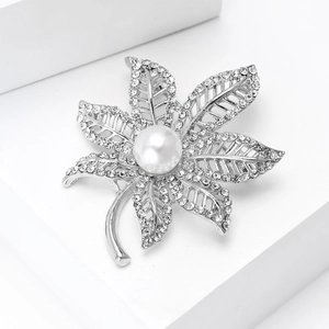 Detailed close-up of maple leaf brooch with silver plating, crystals and a central pearl