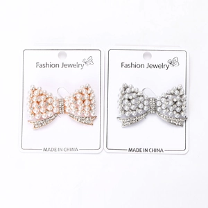 Vue détaillée de broches nœuds en alliage doré et argenté avec perles et strass brillants