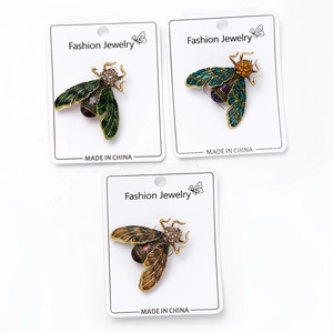 Detailed macro view of three crystal bee brooches with enamel wings on white card