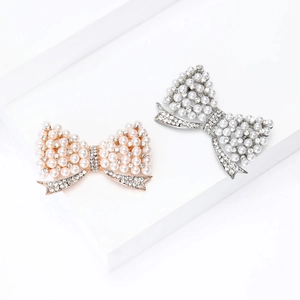 Élégante broche nœud avec perles et strass sur supports géométriques blancs minimalistes