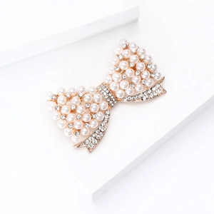 Détail de la broche nœud en or rose avec perles blanches et strass micro-pavés