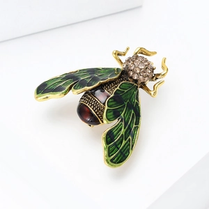 Macro shot of vintage insect brooch with green enamel wings and red crystal body