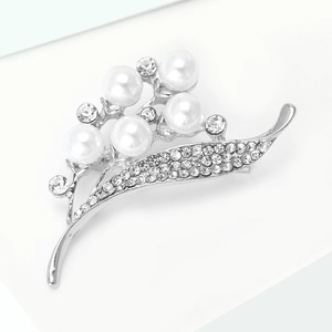 Gros plan sur une élégante broche fleurie en perles avec branches argentées et strass