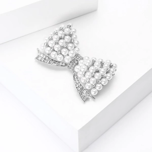 Gros plan détaillé d'une broche nœud avec perles d'imitation et strass sur métal argenté