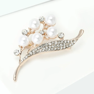 Vue macro d'une broche muguet dorée ornée de perles blanches et de strass étincelants
