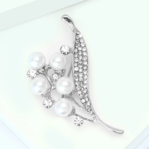 Vue macro d'une broche muguet en alliage d'argent avec des perles blanches et strass