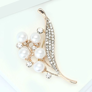 Détail de la broche feuille dorée avec perles d'imitation blanches et strass brillants