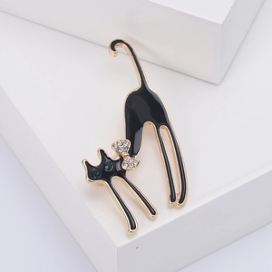 Détail de l'élégante broche chat en émail noir avec yeux en cristal vert et nœud zircon