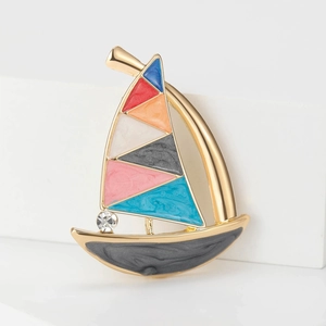 Macro detail of enamel sailboat brooch with colorful sails and sparkling diamond inlay