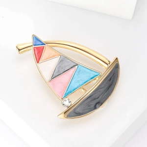 Detailed macro of the colorful enamel sailboat brooch with gold alloy frame and crystal