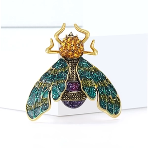 Close-up of vintage gold bee brooch with green enamel wings and yellow rhinestones