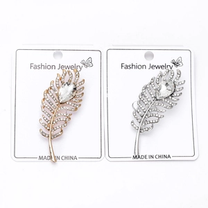 Detail of elegant gold and silver feather brooches with crystals and teardrop stones