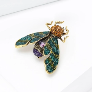 Macro detail of a vintage bee brooch with green enamel wings and amber crystals