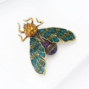 Detailed macro view of insect brooch with gradient enamel wings and orange rhinestones