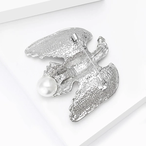 Vue détaillée de la broche aigle en argent avec perle blanche et texture métallique