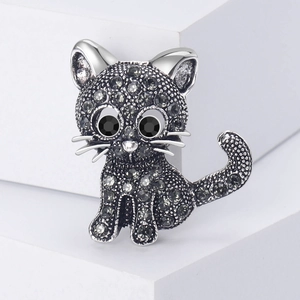 Vintage cat brooch with dark grey rhinestones on a minimalist white platform