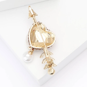 Détail du fermoir à épingle au dos de la broche coeur dorée ornée d'une perle blanche