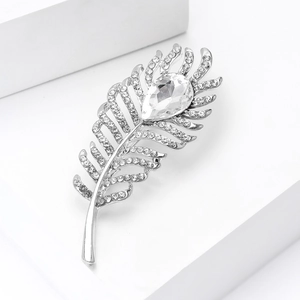 Macro detail of elegant silver feather brooch featuring sparkling rhinestones and teardrop stone