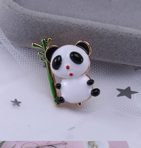 Détail macro d'une broche panda en émail avec bambou sur velours et tulle