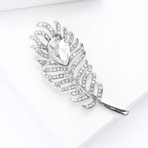 Detailed macro view of silver feather brooch with a large pear-cut crystal and zircons