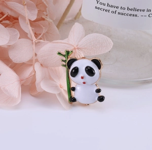 Vue détaillée de la broche panda en émail avec bambou vert sur un fond floral rose élégant