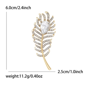 Exquisite gold feather brooch with white crystals and a teardrop diamond on white background