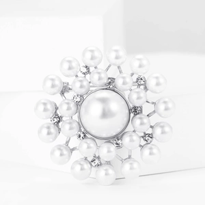 Macro shot of elegant silver flower brooch featuring white pearls and sparkling rhinestones