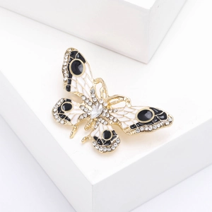 Détail macro d'une broche papillon en émail avec base dorée et strass brillants