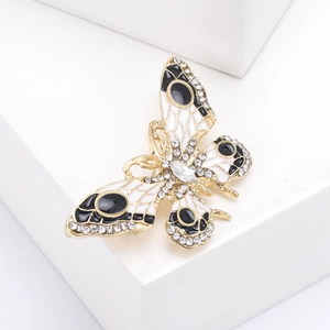 Détail de la broche papillon dorée avec émail noir et blanc et strass scintillants