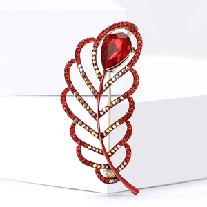 Elegant gold hollow leaf brooch with red rhinestones and teardrop gem on a white stand