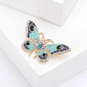 Vue détaillée de la broche papillon avec émail bleu et strass brillants sur métal doré