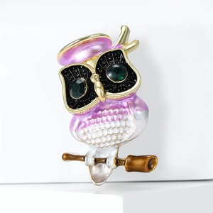 Macro shot of owl brooch with purple enamel finish and green gemstone eyes detailing