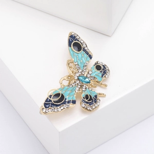 Détail d'une broche papillon dorée avec émail bleu et ailes serties de strass