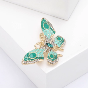 Vue détaillée d'une broche papillon en émail vert ornée de strass brillants et dorés