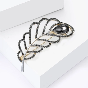 Detailed close-up of a hollow leaf brooch with black crystals and teardrop gemstone