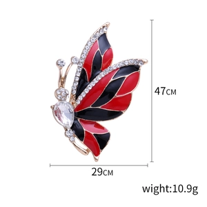 Elegant gold butterfly brooch with red enamel and rhinestones on a clean white background