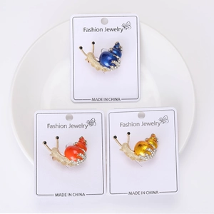 Detailed close-up of three colorful enamel snail brooches on jewelry cards