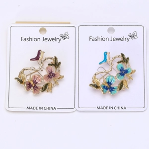 Detailed macro view of enamel flower and bird brooches in pink and blue floral designs