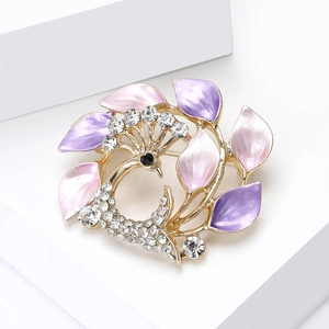 Détail d'une broche paon élégante avec ailes en émail rose et strass blancs brillants