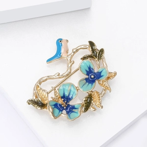 Detailed close-up of Chinese style bird and blue enamel flower brooch with gold plating