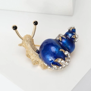 Macro detail of snail brooch with blue enamel shell and sparkling crystal inlay