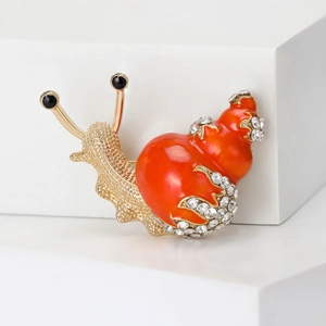 Detailed macro view of orange enamel snail brooch with sparkling rhinestones and gold alloy base