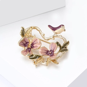 Detail of elegant enamel flower and bird brooch with pink gradient petals and gold finish