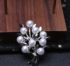 Macro view of silver tree brooch with white pearls against black starry mesh background
