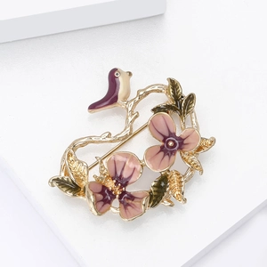 Detail view of bird and flower brooch featuring purple enamel petals and gold branches