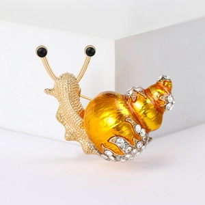 Macro shot of creative snail brooch showing yellow enamel shell and crystal details