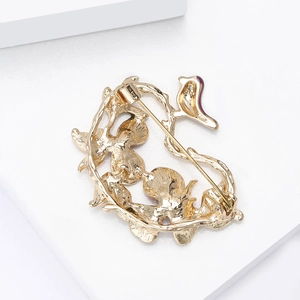 Detailed back view of golden flower and bird brooch showing the safety pin fastener